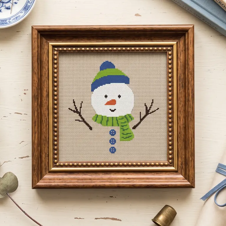 Snowman head cross stitch with stick arms and buttons in a square wooden frame.